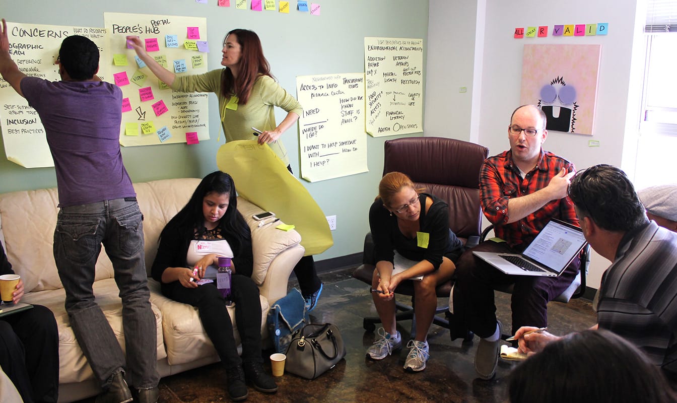 A Code for America field worker speaks to job seekers while others map CareerPathNOLA user needs on the wall