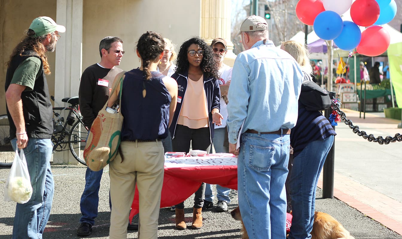 A Code for America field worker speaks to a group of people at a job fair