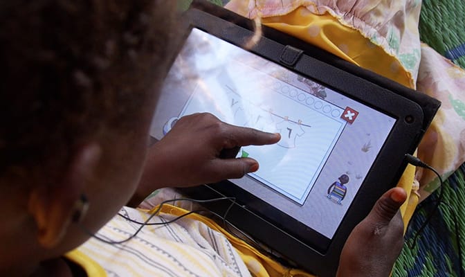 A child plays an educational game on a tablet provided by Google and War Child.