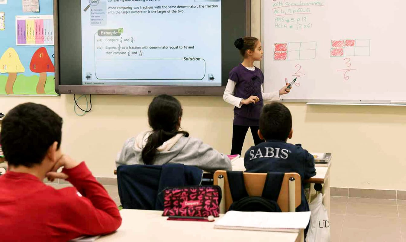 A group of students discuss a math problem in a classroom.