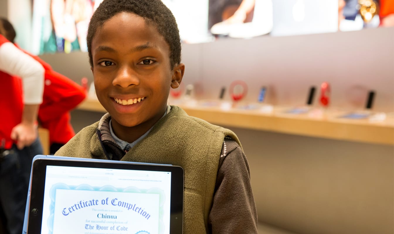 A Code.org student proudly shows off his certificate after completing a class.