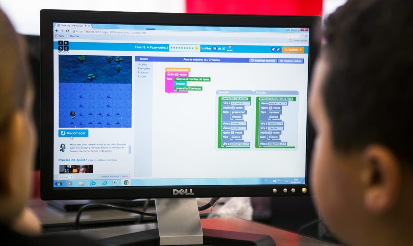 A child and his instructor look at lessons online during a coding class.