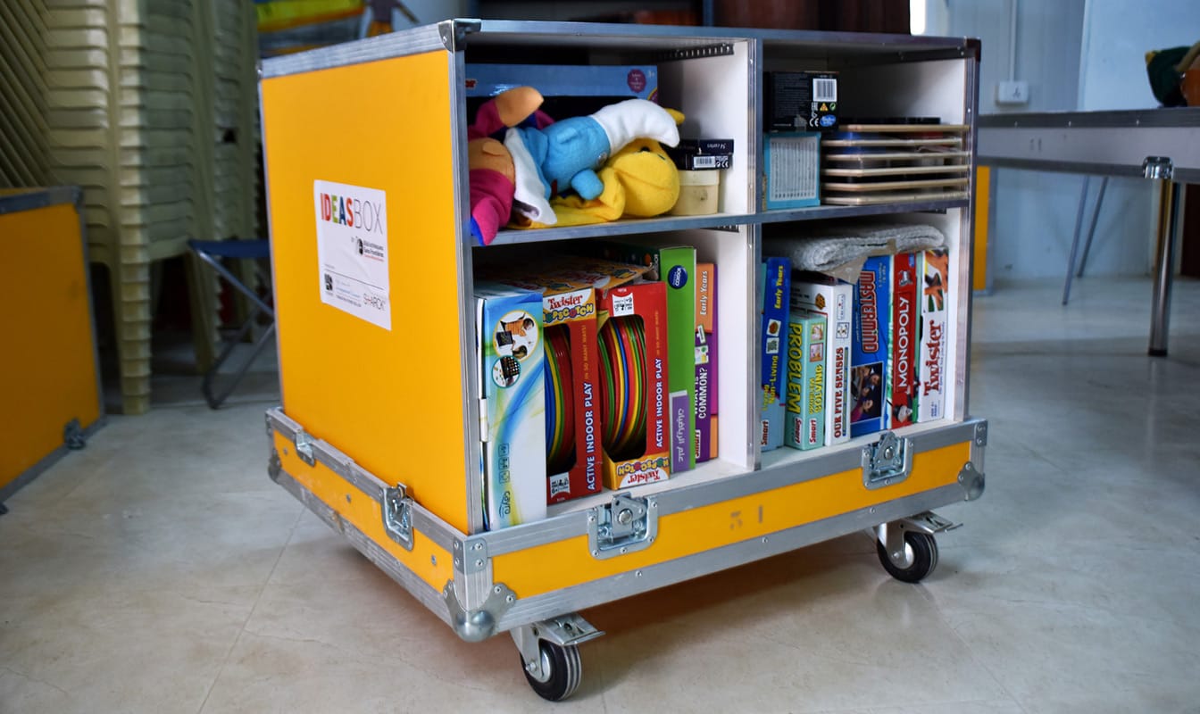 An Ideas Box containing toys, games, and educational materials sits open inside a classroom.