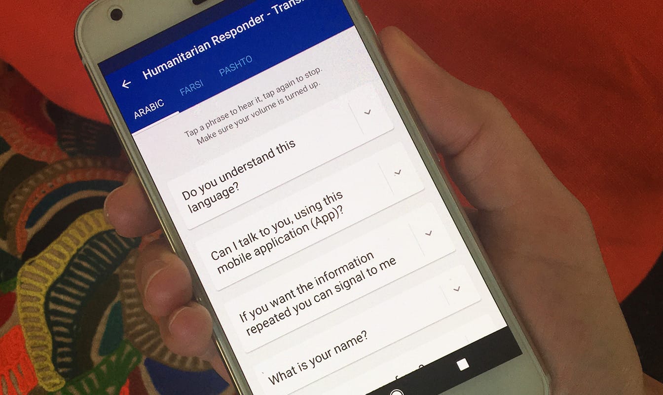 A Mercy Corps field worker holds a smartphone while using the Translation Cards Android app.