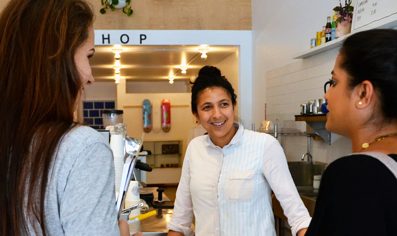 Three woman discuss technology and design in a coffee shop.