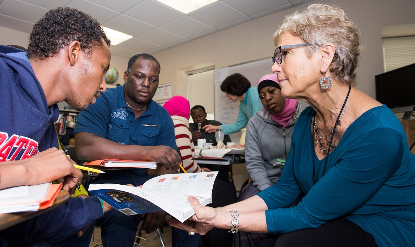 A Social Finance field worker shows an open book to two minority students