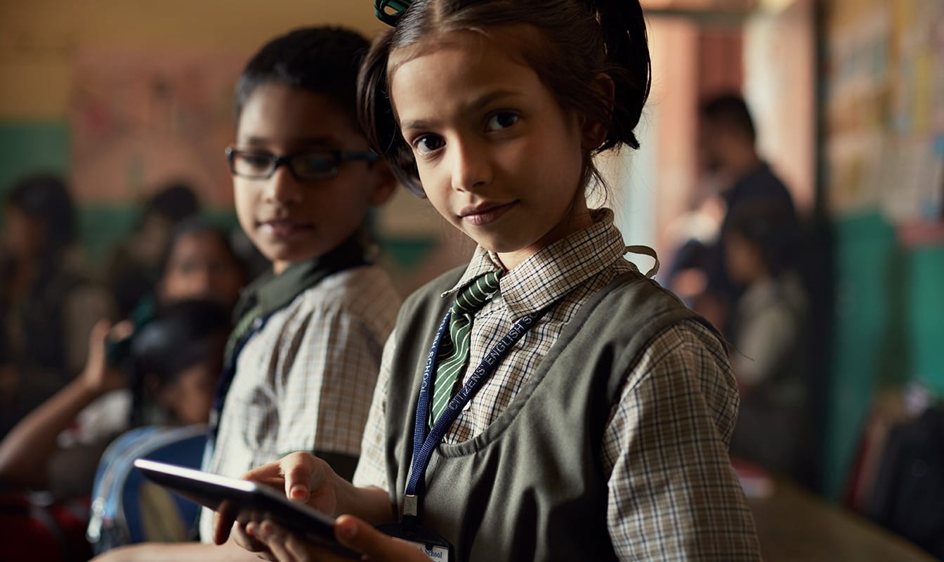 Une jeune fille utilise une tablette pour lire un livre traduit dans sa langue maternelle.