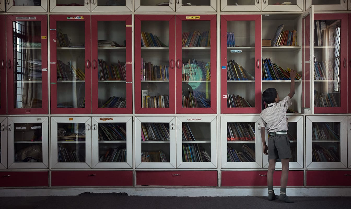 Un jeune garçon attrape un livre dans la bibliothèque d'une classe.