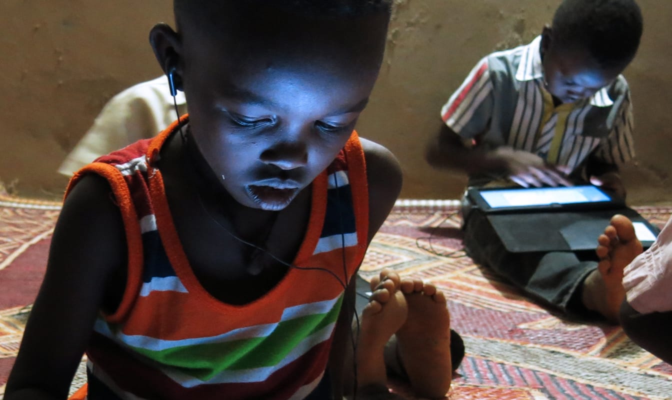 Young boys play an educational game on their tablets.